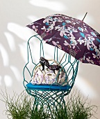 White patterned handbag, floral rain umbrella, black pump on chair