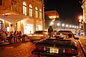 Menschen sitzen vor Café, außen, Autos, abends in Tallinn