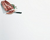 Lamb with garlic, herbs, knife and board on white background