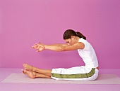 Pilates - Boomerang: Frau sitzt, Arme vorne, Beine übereinander,Step7