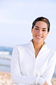 Portrait of pretty woman wearing knitted zipper standing on beach, smiling