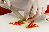 Chilli pepper being cut into small cubes with knife, step 3