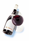 Glass with red wine and bottle on white background