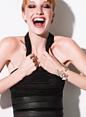 Ecstatic woman wearing dark eye shadow and black top laughing with eyes closed