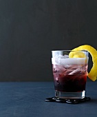 Royal Bramble with blackberry, lemon peel and ice in glass
