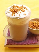 Milk coffee with cream and praline in cup