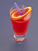 Red Russian cocktail with ice, straw and orange slice in glass