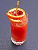 Bloody ginger cocktail with orange and ice cubes in glass
