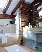 Bathroom with sloping ceiling and partition of wooden beams