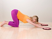 Blonde woman in sportswear performing flow tonic exercise on wooden floor