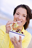 Brunette woman in yellow sweater with salad in bowl