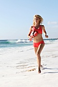 Frau läuft am Strand mit einer Rettungsboje