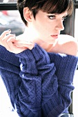 Pensive woman wearing blue sweater propped on elbows, looking away