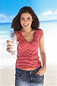 Frau am Strand, Wasserflasche in der Hand haltend