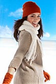 Portrait of pretty woman wearing sweater, scarf and hat looking over shoulder, smiling