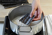 Seaweed being placed in pot for preparation of sushi, step 2