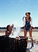 Man in bath tub splashing water on woman, laughing