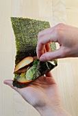 Rice and fruits being placed on nori sheet for preparation of sushi, step 2