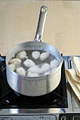 Fish dumpling being boiled in sauce pan on stove