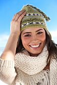 Portrait of pretty woman wearing beige coloured scarf and green knit cap, smiling