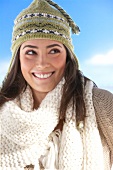 Pretty woman wearing beige coloured scarf and green knit cap looking up, smiling