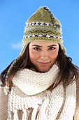 Portrait of pretty woman wearing beige coloured scarf and green knit cap, smiling