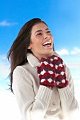 Pretty woman wearing white sweater with woollen gloves smiling while looking up