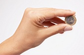 Euromünze, gehalten zwischen zwei Fingern