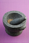 Granite mortar with pestle on purple background