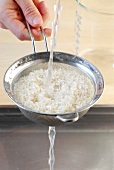 Rice being washed with water in sieve, step 1