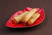 Three spring rolls on red plate