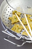 Close-up of steamed salmon wontons with chopsticks in steamer