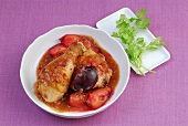 Chicken drumsticks with plum sauce in bowl with coriander leaves