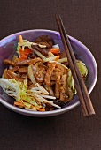 Chop suey with pork, carrots, cabbage and mushrooms in bowl