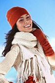 Portrait of happy young woman wearing red knitted hat, gloves and scarf, smiling widely