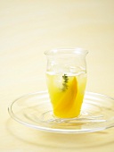 Glass of mango and orange punch with thyme