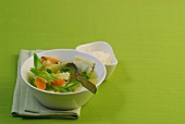 Bowl of ravioli with vegetable stew on green background