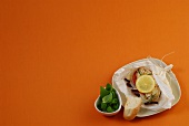 Chicken with lemon wedge in parchment packet on plate