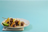 Duck skewers with orange and coconut sauce on plate