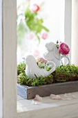 Porcelain figures with flowers on tray with moss