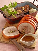 Stuffed and roasted meat on wooden board with roasted meat and dumplings in pot