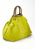 Close-up of green suede handbag on white background