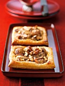 Two pieces of baked pastry filled with mushroom and almond on serving tray