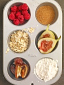 Figs, raspberries, sugar and oatmeal flour in cupcake mould, muffin ingredients