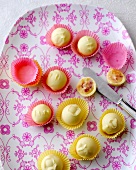 Strawberry yogurt balls and mango lassi chocolates in paper cups on plate