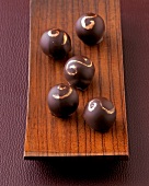 Five figs and chilli chocolates with gold trim on wooden plate