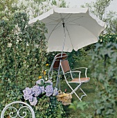zwei Gartenstühle und Sonnenschirm mit Efeuhecke