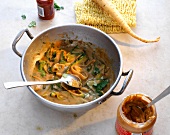 Asian egg noodles with zucchini and peanut sauce in wok