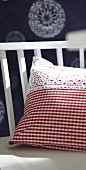 Close-up of red and white plaid patterned pillow with lace on chair