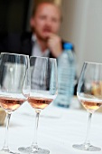 Three glasses of grapes wine on table with man sitting in background